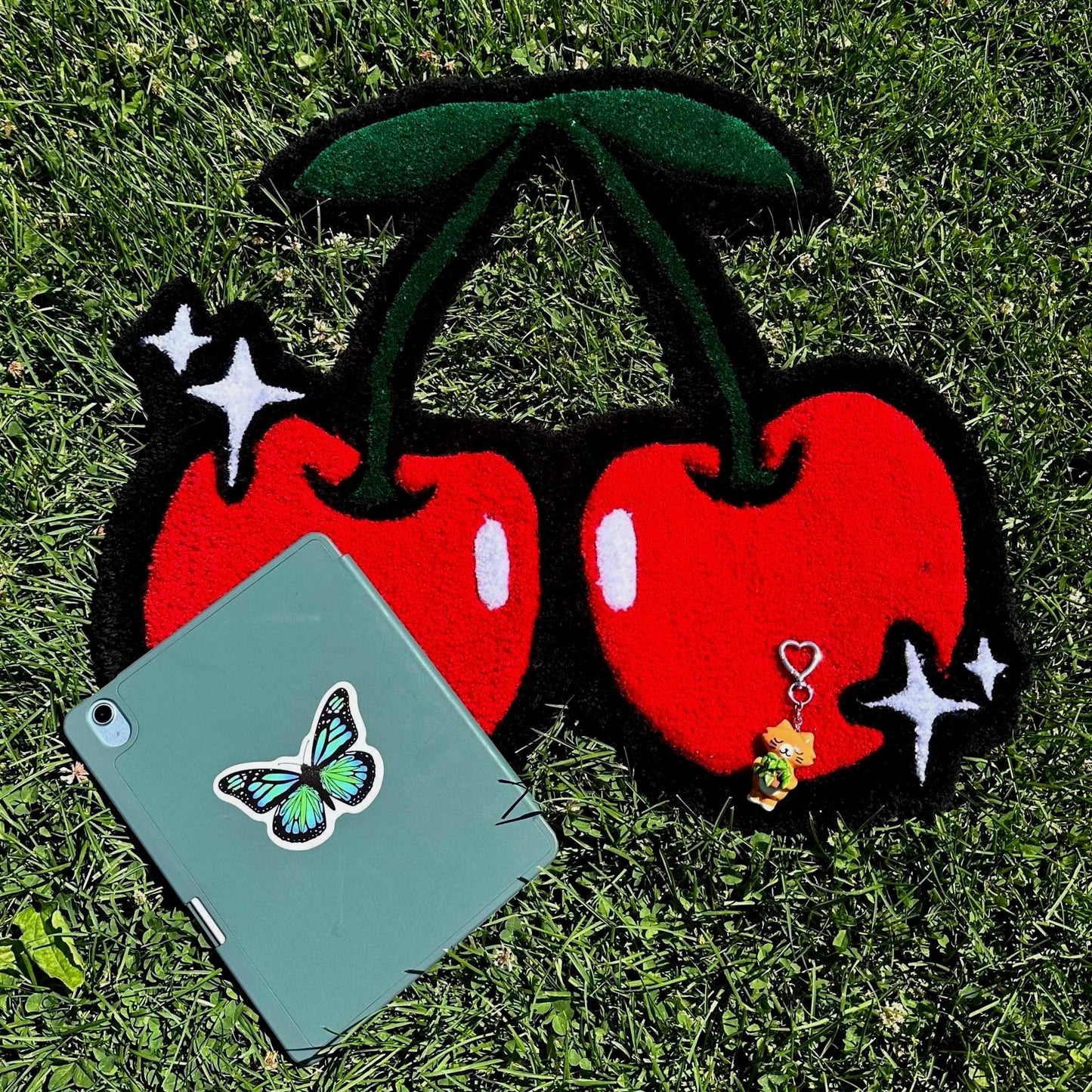 Two red cherries with black stems on a grassy background