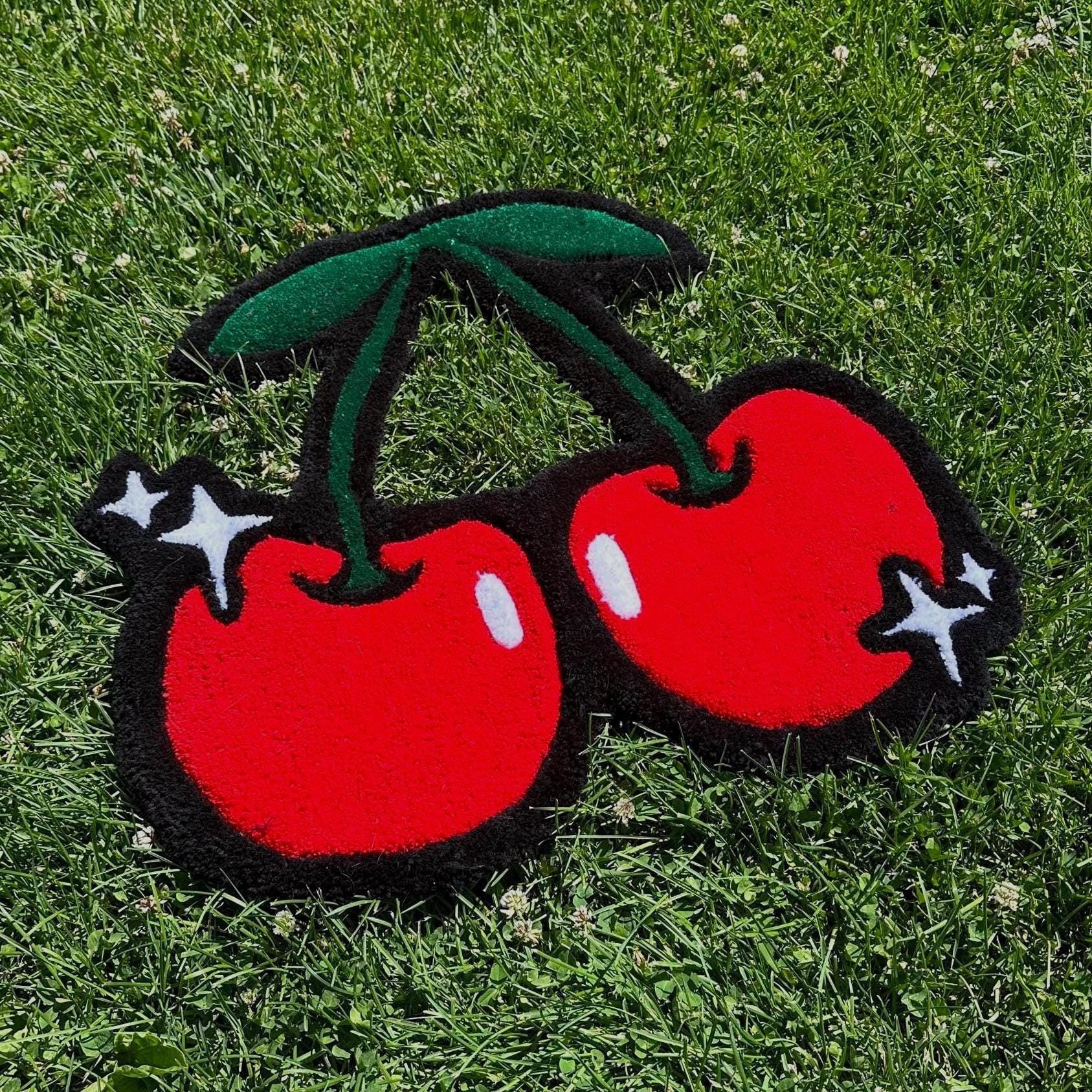 Two red cherries with green stems on a grass background