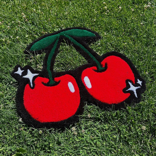 Two red cherries with green stems on a grass background